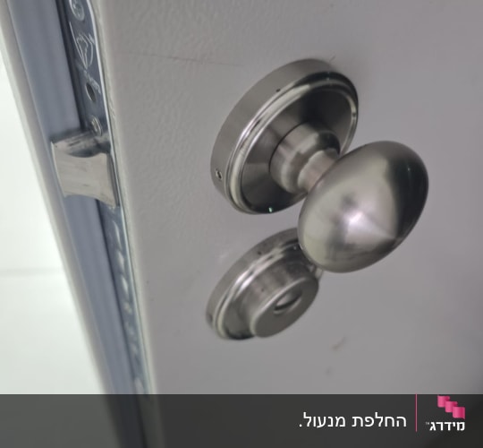 ידית דלת מתכת על דלת לבנה